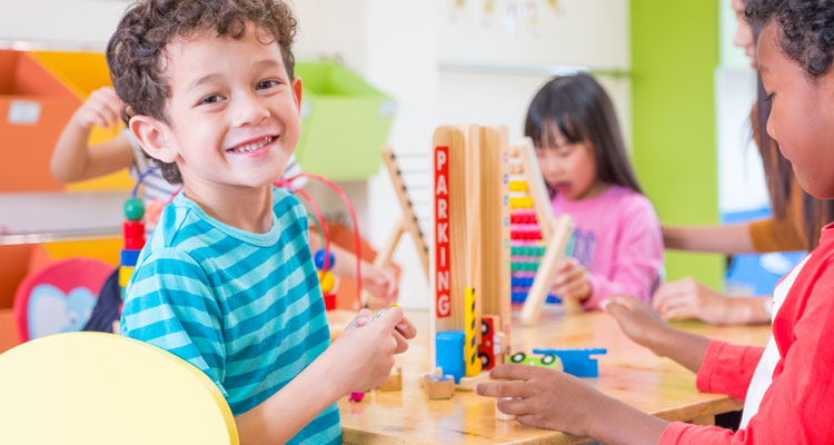 Smiling young boy playing with blocks in daycare