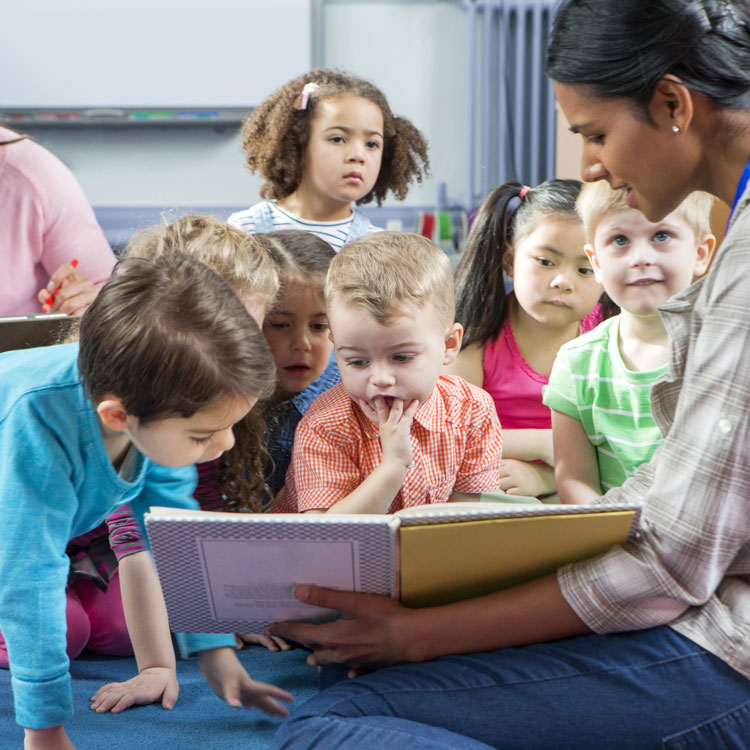 Storytime at Nursery, worker reading book to a number of toddlers