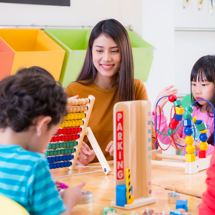 Teacher and toddlers in daycare playing at table